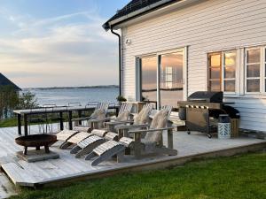 a deck with chairs and a picnic table and a grill at Villa Borgvåg - A unique Seafront Villa in the heart of Lofoten in Bøstad