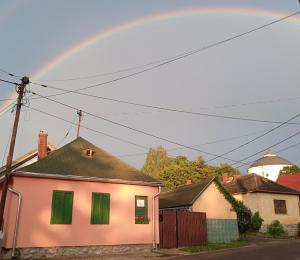 un arco iris sobre una casa blanca con persianas verdes en Liána Vendégház, en Szilvásvárad