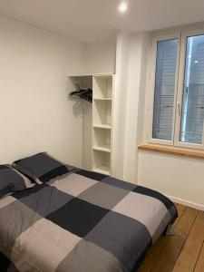 Un dormitorio con una cama en blanco y negro y una ventana en Le péageois : Appartement lumineux et calme, en Bourg-de-Péage