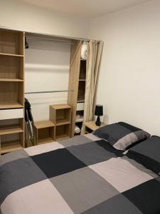 1 dormitorio con cama y estanterías en blanco y negro en Le péageois : Appartement lumineux et calme, en Bourg-de-Péage
