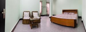 - une chambre avec un lit et deux chaises dans l'établissement Nyla homestay Naharlagun, à Bacha