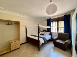 a bedroom with a four poster bed and a chair at The Fortuna Hotel and Cafe in Kabale