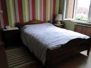 a bed in a bedroom with striped walls and a window at Feel at home in Leuven in Leuven