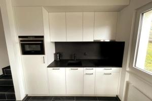 a kitchen with white cabinets and a sink and a window at Wohnung mit fantastischer Aussicht in Trin