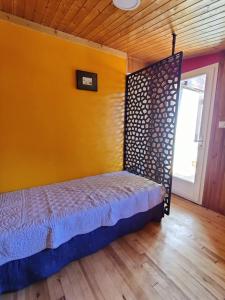 Bett in einem Zimmer mit gelber Wand in der Unterkunft Chalet Ailleurs Appartement à Molines en Queyras in Molines-en-Queyras