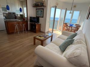 a living room with a white couch and a table at Apartamento en acantilado con wifi y aire acondicionado in Sitges
