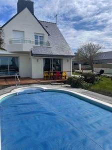 ein großer blauer Swimmingpool vor einem Haus in der Unterkunft Maison spacieuse avec piscine in Guidel