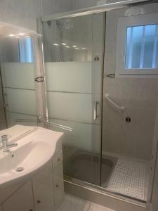 ein Badezimmer mit Glasdusche und Waschbecken in der Unterkunft Maison spacieuse avec piscine in Guidel
