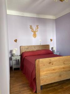 1 dormitorio con cama de madera y manta roja en La reis entursuo, en Frassino