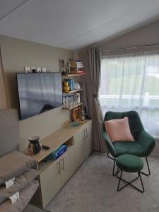 a room with a desk and a chair and a television at Wood Farm Holiday Park in Charmouth