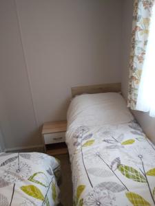 niewielka sypialnia z 2 łóżkami pojedynczymi i oknem w obiekcie Wood Farm Holiday Park w mieście Charmouth