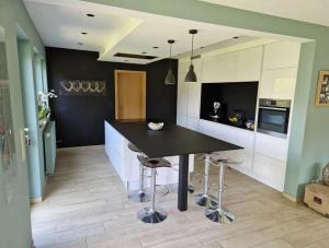 una cocina con mesa negra y taburetes en Chambre London proche du circuit, en Spa