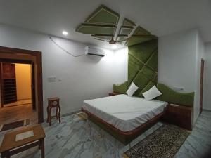 a bedroom with a bed with a green headboard at Hotel Maheshwar Darshan in Maheshwar