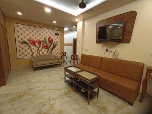 a living room with a couch and a flat screen tv at Hotel Maheshwar Darshan in Maheshwar