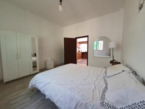 a white bedroom with a bed and a hallway at Karak House in Kerak