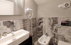 een badkamer met een wastafel, een toilet en een spiegel bij Hotel Cecina Beach in Marina di Cecina