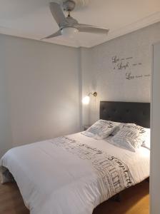 Schlafzimmer mit einem weißen Bett und einem Deckenventilator in der Unterkunft Serendipia Apartamentos 1 in Logroño