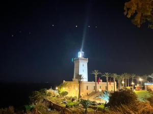 un edificio con una torre de reloj por la noche en Forêt appartement, en Tánger