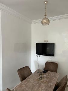 a dining room table with chairs and a television on the wall at Forêt appartement in Tangier