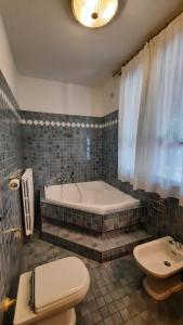 y baño con bañera, aseo y lavamanos. en Elisa Holidays Apartments, en Puegnago sul Garda