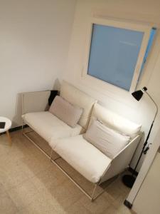 a white couch in a room with a window at Newly renovated 2 bed apartment in Blanes old town 50m from the beach! in Blanes