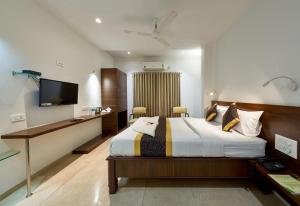 Schlafzimmer mit einem Bett, einem Schreibtisch und einem TV in der Unterkunft Hotel Fortune Inn in Kolhapur
