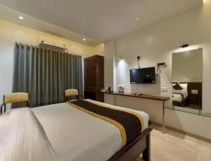 Schlafzimmer mit einem Bett, einem Schreibtisch und einem TV in der Unterkunft Hotel Fortune Inn in Kolhapur