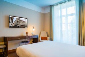 サンティアゴ・デ・コンポステーラにあるホテル コンポステラのベッド、デスク、窓が備わるホテルルームです。