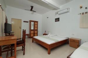 a bedroom with a bed and a desk and a television at Ashirvad Homestay, Ashtamudi Lake, Kollam in Kollam