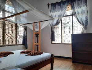 a bedroom with a canopy bed and windows at Kajificheni House in Nungwi