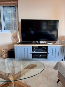 TV grande en un armario azul con mesa de cristal en Amazing view Panorama Eretrias, en Eretria