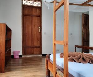1 dormitorio con litera y puerta de madera en Kajificheni House en Nungwi