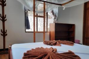 ナングウィにあるKajificheni Houseのタオルが敷かれたベッドのある寝室