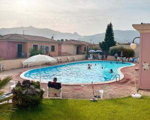 a man sitting in a chair next to a swimming pool at Arcobaleno 1 in Villasimius