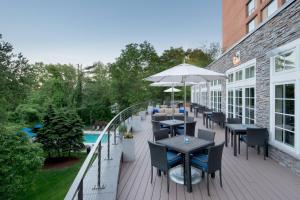 an outdoor patio with tables and umbrellas and a pool at Boston Marriott Burlington in Burlington