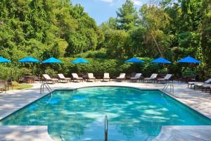 a swimming pool with chairs and blue umbrellas at Boston Marriott Burlington in Burlington