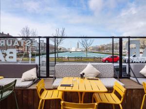 une table et des chaises jaunes sur un balcon avec vue dans l'établissement Mercure Le Havre Centre Bassin Du Commerce, au Havre