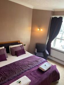 ローチェスターにあるThe Royal Victoria & Bull Hotelのベッドルーム1室(紫のシーツと椅子付きのベッド1台付)