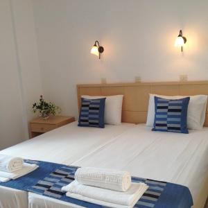 a bedroom with a bed with blue and white pillows at Hotel Kyma in Skala Eresou