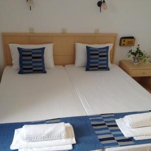 a bedroom with a large bed with blue and white pillows at Hotel Kyma in Skala Eresou