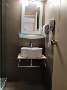 een badkamer met een wastafel en een spiegel aan de muur bij Pantheon Hotel in Atsipopoulo