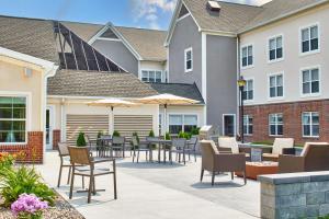 un patio al aire libre con mesas, sillas y sombrillas en Residence Inn by Marriott Rochester West Greece, en Rochester