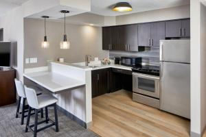 a kitchen with a white counter top and wooden cabinets at Residence Inn by Marriott Rochester West Greece in Rochester