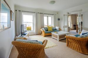 uma sala de estar com um sofá, cadeiras e janelas em Regatta View - Simon's Town em Cidade do Cabo
