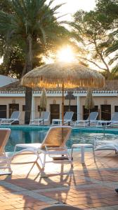 un grupo de sillas y una sombrilla junto a la piscina en Hotel Montepiedra 4''''sup, en Playas de Orihuela
