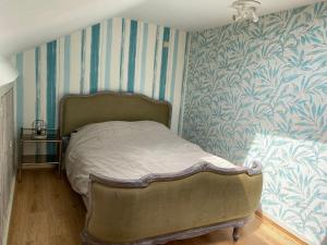 Ce lit se trouve dans une chambre avec du papier peint bleu et blanc. dans l'établissement Quiétude à la ferme, à Houdremont