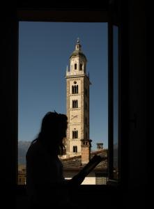 una persona mirando por la ventana a una torre del reloj en Albergo San Michele, en Tirano