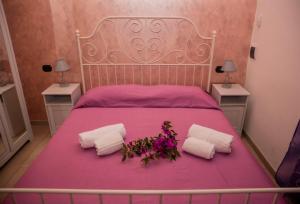 różowe łóżko z dwoma białymi ręcznikami i kwiatami w obiekcie Il Poggio Veronica w mieście San Nicola