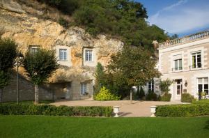 a large white house with a mountain behind it at Hotel Les Hautes Roches in Rochecorbon