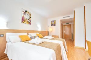 1 dormitorio con 2 camas con sábanas blancas y almohadas amarillas en Hotel Don Manuel, en Gijón